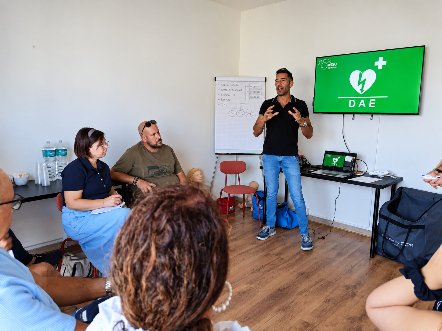 Docente durante una lezione BLSD con partecipanti, manichini e DAE didattico